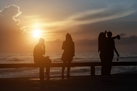 The tourist Both women and men take photos and enjoy the scenery. Sunrise from the seaの写真素材