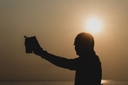 silhouette of a man with a smartphone Shoot yourself with the sunrise landscapeの写真素材