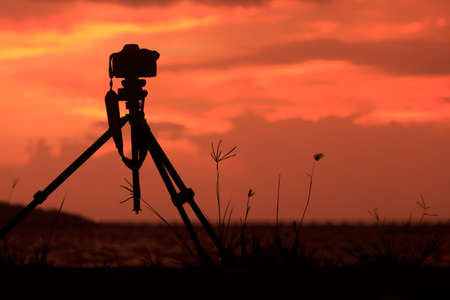 photo camera with tripod At sunset, dusk, colors and shapes of cloudsの写真素材