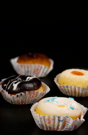 Small donuts of various flavors on a black background.の写真素材