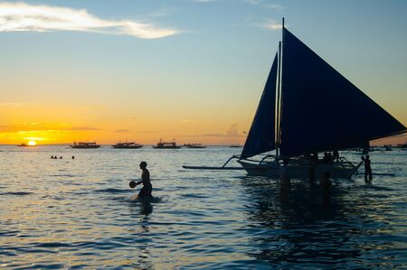 Beautiful colorful sunset over fishing boats and people in water