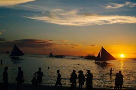 Beautiful colorful sunset over fishing boats and people in waterの写真素材