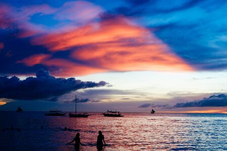 Beautiful colorful sunset over fishing boats and people in water