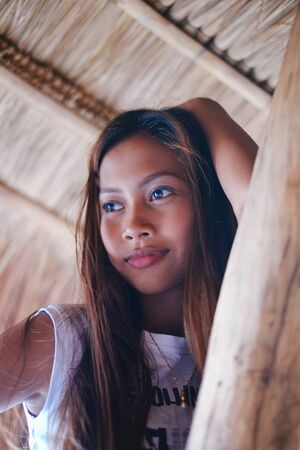 Portrait of a beautiful native Asian girl climbing on the sunshade umbrellaの写真素材