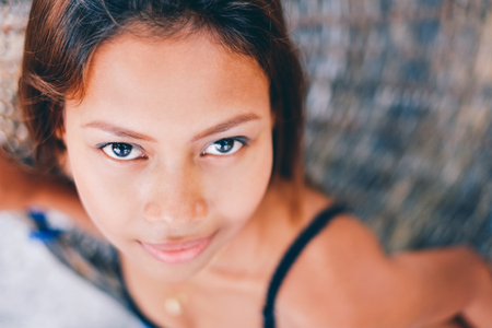 Portrait of young sexy beautiful girl sitting on rattran hammock, bleurry backgroundの写真素材