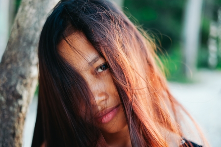 Natural portrait of beautiful young Asian girl smiling with messy hairの写真素材
