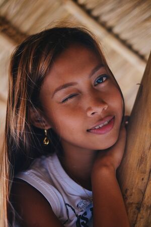 Portrait of a beautiful native Asian girl climbing on the sunshade umbrella