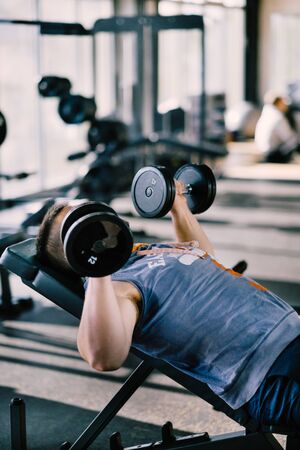 Young handsome man working out with dumbbells in a fitness gymの写真素材