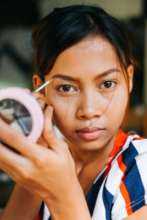 Young beautiful girl applying makeup. Girl coloring eyebrows with eyebrow linerの写真素材