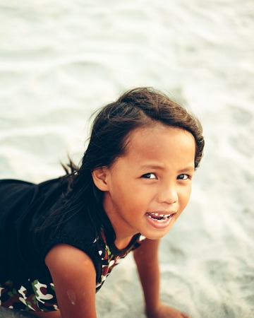 Playful little girl on the beah crolling on the sandの写真素材