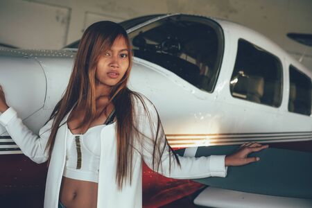 Beautiful female portrait in the airplane hangar, with modern aircraftの写真素材