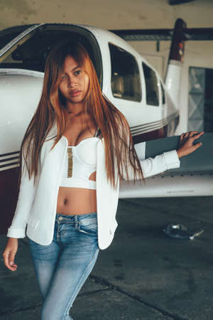 Beautiful female portrait in the airplane hangar, with modern aircraftの写真素材
