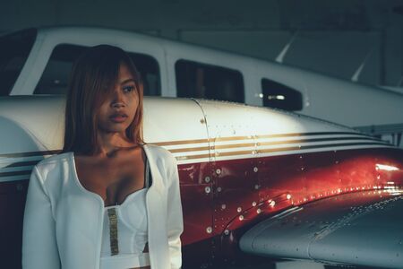 Beautiful female portrait in the airplane hangar, with modern aircraftの写真素材