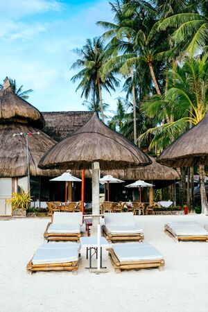 Nipa hut sun shade with bamboo sunbeds on white coral sand beach