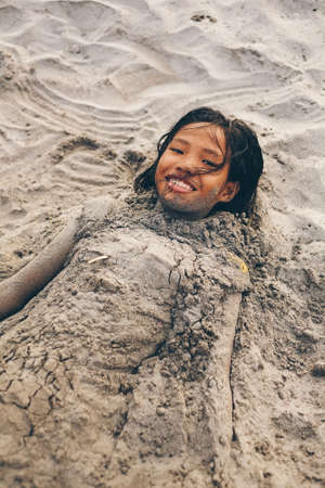 Young little girl playing on the beach covered with the sandの写真素材