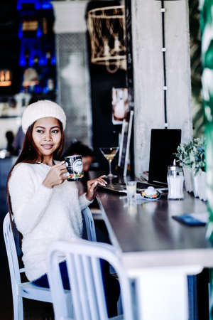 Beautiful young girl student chilling in a club or cafe, drinking teaの写真素材