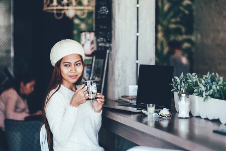 Beautiful young girl student chilling in a club or cafe, drinking teaの写真素材