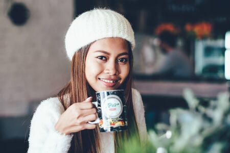 Beautiful young girl student chilling in a club or cafe, drinking teaの写真素材