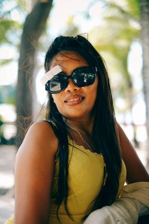 Happy portrait of Asian woman with sunglasses in summertime on the beachの写真素材