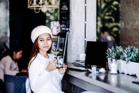 Beautiful young girl student chilling in a club or cafe, drinking tea.の写真素材