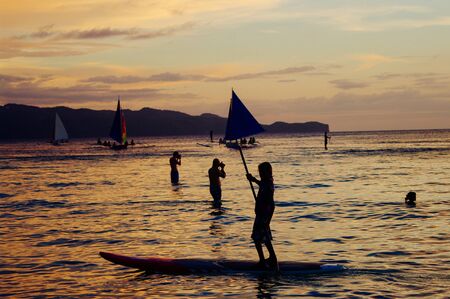 Beautiful golden sunset over fishing boats and people in water