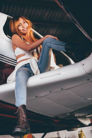 Beautiful female portrait in the airplane hangar, with modern aircraftの写真素材