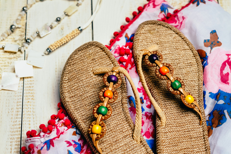 Flat lay of summer object with summer scarf and slippers on white wooden backgroundの写真素材