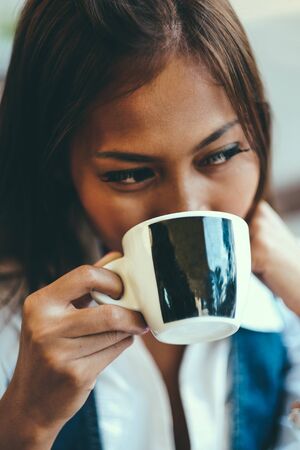 Close-up portrait of beautiful young woman holding cup of tea or coffee, Selective Focus.の写真素材