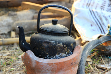 black old kettle been used for a long time on a small brown furnace.の写真素材