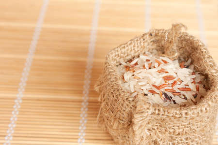 Raw rice in woven bag on bamboo padの写真素材