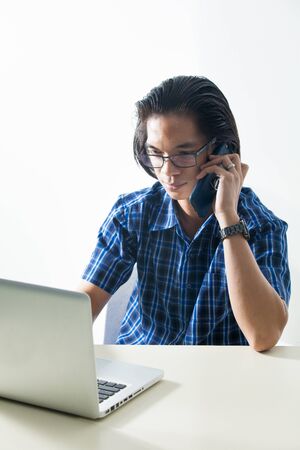 Man on a computer talking on the phoneの写真素材