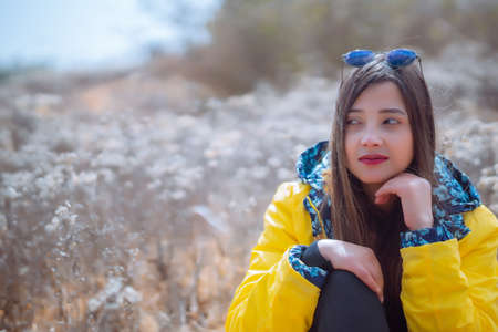 Beautiful girl in a yellow jacket with a dry flower fieldの写真素材