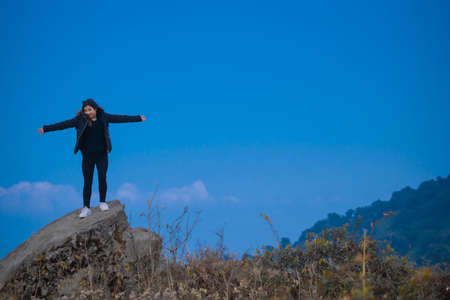A young woman standing on a rock on a cliffの写真素材