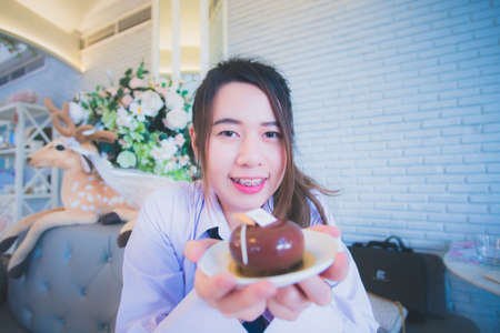 Young female student eating cake in a coffee shopの写真素材