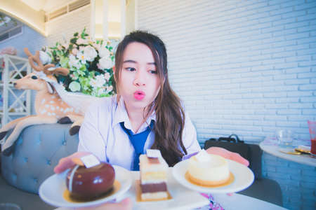 Young female student eating cake in a coffee shopの写真素材