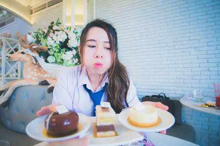 Young female student eating cake in a coffee shopの写真素材