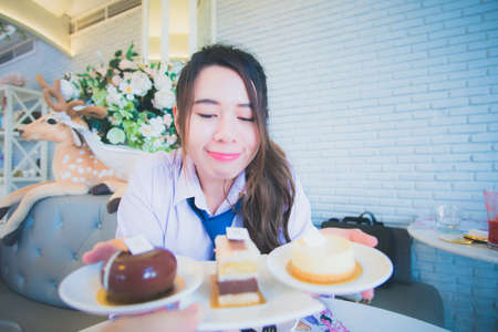 Young female student eating cake in a coffee shopの写真素材