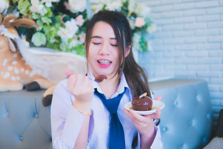 Young female student eating cake in a coffee shopの写真素材