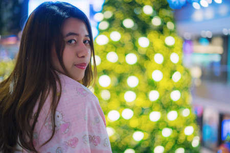 Beautiful girl with Christmas tree and bokehの写真素材