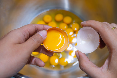 Close up of woman's hands break the egg and separate the white from the yolk on cake making process
