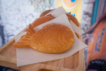 Homemade Japanese fish Taiyaki cake with sweet red bean fillings on wooden dish and Japanese style curtains background.の写真素材