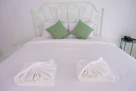 White towel on bed with green pillow vintage style decoration in guest room for hotel customer.の写真素材