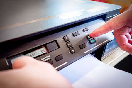 Close up of hand press button on panel of printer in the home office. Employee use printer in office...