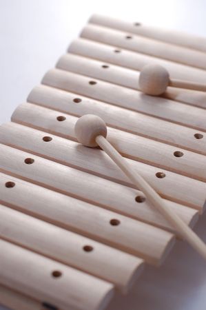 Wooden xylophone on a white background with two sticks.