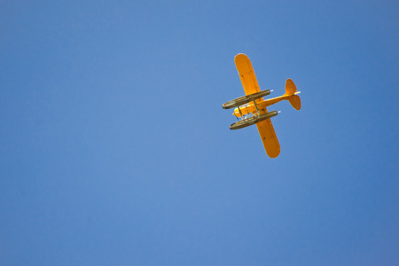 Bright yellow plane flying in blue sky, view from below