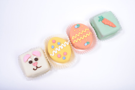 Four small bright Easter cakes in a form of bunny and eggs, on white background