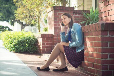 Young attractive woman with phone on sunny streetの写真素材