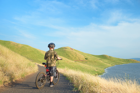 Happy boy riding his mountain bike on trail in hillsの写真素材