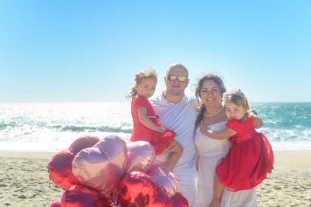 Happy hugging family on the beach with balloonsの写真素材