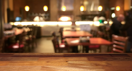 Empty wooden table top with blurred restaurant on backgroundの写真素材